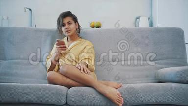 穿着浴袍的年轻女子<strong>坐在沙发</strong>上的房间里。 他<strong>坐在沙发</strong>上喝咖啡看电视。 舒适